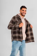 Sobrecamisa de hombre con cuello camisero, botones frontales y bolsillos de parche en el pecho. Presenta un estampado a cuadros en tonos marrones, negros y beige.