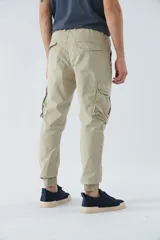 Pantalón cargo verde militar de corte slim, con elástico en la cintura, cordón ajustable, bolsillos cargo con botones y puños elásticos.