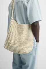 Bolso de hombro color crudo, tejido en macramé de algodón. Tiene un compartimento principal con cierre de imán y un bolsillo plano interior.