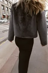 Chaqueta de cuello redondo y manga larga con tejido exterior efecto pelo e interior efecto ante. Presenta bolsillos delanteros de vivo y cierre frontal con alamares metálicos.