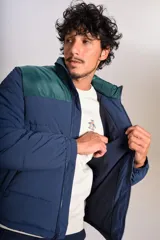 Campera puffer con diseño bicolor, cuerpo en azul marino y canesú superior en verde oscuro. Presenta cuello alto, cierre frontal completo y puños elásticos.