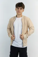 Campera bomber color beige de nylon con cierre frontal y puños y cintura acanalados.