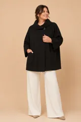Chaquetón de lana color negro, con cuello alto, mangas tres cuartos y bolsillos frontales. Presenta un diseño holgado y cierre frontal con un botón.