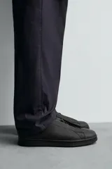 Zapatilla de estilo minimalista confeccionada en piel, con diseño de cordones ocultos, horma redonda y suela a tono.