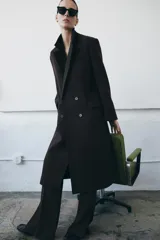 Abrigo oversize de Zara Woman Collection confeccionado en hilatura con lana. Presenta cuello con solapa de muescas, manga larga, bolsillos con solapa en el delantero y cierre frontal cruzado con botones. Incluye forro interior.