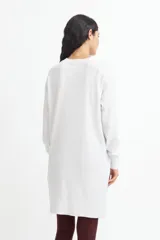 Vestido tipo sweater color blanco, de corte recto y largo hasta la rodilla, con cuello redondo y mangas largas.