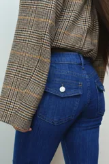Pantalón jean de denim azul elastizado, de tiro bajo y corte ajustado con botamanga acampanada. Presenta diseño clásico de cinco bolsillos y cierre frontal con botón y cremallera.