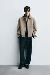 Sobrecamisa color beige de corte cuadrado, con cuello solapa, manga larga con puños abotonados, bolsillos laterales y cierre frontal con botones.