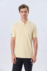 Remera polo piqué de algodón color amarillo, con cuello y puños acanalados, y cierre frontal de botones.