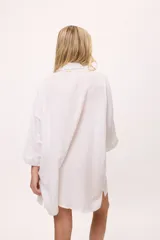 Vestido camisero negro de algodón, con mangas tres cuartos y cuello camisero. Presenta detalles de costura en zigzag color naranja en el cuello y en los puños.