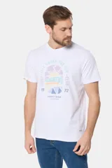 Remera de cuello redondo y manga corta, confeccionada en tejido de algodón con acabado jaspeado. Presenta un estampado frontal con temática de surf y estilo retro en tonos pasteles.