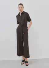 Mono largo de lino y lyocell en color marrón, con diseño recto, cuello camisero, manga corta, bolsillos laterales y cierre delantero con botones. Incluye un cinturón ajustable del mismo tejido con hebilla metálica.