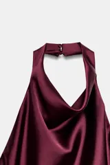 Vestido corto de tejido satinado color bordó, con cuello halter, espalda descubierta y detalle de frunces en la cintura.