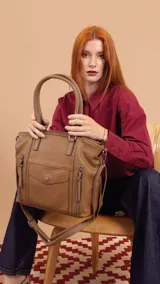 Cartera tipo tote de diseño estructurado en símil cuero, con doble asa rígida y correa regulable. Presenta múltiples bolsillos frontales con cierre y solapa, ofreciendo un estilo versátil y espacioso.