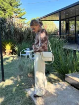 Cartera tipo bandolera de cuero color crudo, con solapa frontal y cierre. Incluye dos correas desmontables, una corta y una larga, y cuenta con bolsillo interior.