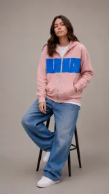 Campera con capucha y cierre frontal, color rosado con una franja horizontal azul en el pecho y logo bordado en color naranja.