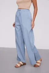Pantalón celeste de algodón, de tiro alto y corte ancho, con cintura elástica ajustable mediante cordón y aberturas laterales en los bajos.