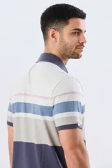 Remera polo de manga corta con diseño de franjas horizontales en tonos azul, salmón, celeste y beige. Cuenta con cuello clásico y cierre frontal de dos botones.