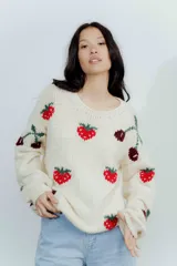 Buzo de lana merino color crema con diseño tejido de frutillas y cerezas en tonos rojos y bordó. Presenta cuello redondo, mangas largas y un corte holgado.