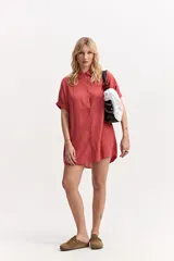 Vestido camisero corto color coral, de silueta amplia y suelta, con manga corta, cuello clásico y cierre frontal de botones.