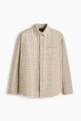 Camisa de sarga de algodón con estampado a cuadros en tonos beige y marrón, cuello americano, cierre frontal de botones, un bolsillo de parche en el pecho y mangas largas.