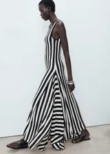 Vestido largo de punto fino con diseño a rayas verticales en blanco y negro, sin mangas, con cuello redondo y corte evasé.