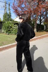 Conjunto de dos piezas confeccionado en tejido plush aterciopelado color negro. Incluye un buzo de corte cropped con cuello redondo y mangas largas, y un pantalón estilo cargo de silueta holgada con bolsillos laterales funcionales y puños ajustables en los tobillos.