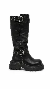 Bota alta de cuero sintético negro con suela track gruesa, costuras blancas en contraste y dos tiras con hebillas metálicas y tachas en la caña.