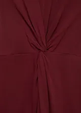 Vestido midi de algodón, sin mangas y con cuello redondo. Presenta un diseño recto con un detalle drapeado frontal tipo nudo en la cintura.