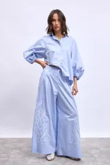 Pantalon de corte ancho y tiro alto, color azul marino, con bordados florales en color crema en la parte inferior de las piernas.