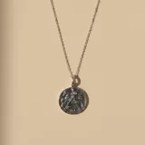 Collar de plata 925 con cadena fina y dije circular grabado con la imagen de San Jorge luchando contra el dragón, con un pequeño detalle de piedra incrustada.
