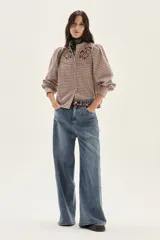 Camisa de manga larga con diseño de cuadros en tonos rosa y bordó. Presenta cuello mao, cierre frontal con botones y detalles de bordados florales en la parte superior del pecho. Las mangas son abullonadas con puños ajustados.