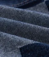 Campera de jacquard de algodón con diseño patchwork de cuadros en tonos azules. Presenta cuello inglés, cierre frontal con botones metálicos, mangas largas y bolsillos delanteros.