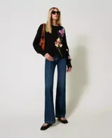 Sweater negro de algodón con cuello redondo, manga larga y corte holgado. Presenta incrustaciones florales decoradas con bordados a mano.