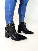 Bota tejana de cuero, combinada en color tostado, animal print de leopardo y puntera en charol negro. Cuenta con taco de madera, detalle de hebilla lateral y ojales metálicos en la parte superior.