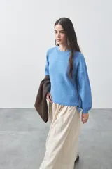 Sweater de tejido liviano con silueta relajada, hombros caídos y mangas largas con puños ajustados. Presenta cuello redondo y lazos ajustables en el bajo.