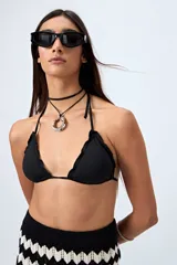Top de bikini negro con tirantes finos y volados en el borde.