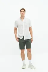 Camisa de manga corta con cuello camisero, confeccionada en una mezcla de lino y algodón. Presenta un diseño a rayas verticales en tonos claros, cierre frontal con botones y un bolsillo en el pecho con logo bordado.