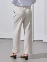 Pantalón de lino de corte recto y tiro medio, con pretina elástica ancha y lazo de ajuste frontal. Presenta bolsillos laterales verticales y bolsillos traseros.