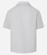 Camisa de corte boxy fit, color blanco, con cuello bowling, cierre frontal con botones y manga corta. Confeccionada en tejido de algodón con textura jacquard.