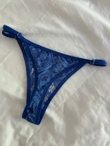 Bombacha de encaje azul con tiras regulables en los costados.