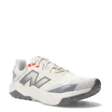 Championes New Balance Nitrel, diseñados para trail running y uso urbano, de color beige con detalles en gris y toques de naranja. Presentan capellada de malla transpirable con refuerzos, entresuela acolchada y suela con tracción especializada.