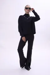 Pantalón negro de corte acampanado con aberturas en el ruedo.