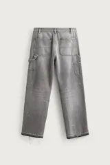 Jeans relaxed fit de tiro medio y pernera recta confeccionados en denim de algodón rígido, con diseño de carpintero que incluye bolsillos superpuestos y roturas localizadas en el frente.