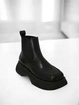 Bota Chelsea de cuero negro con elásticos laterales, tira trasera y suela track.