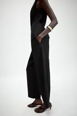 Pantalón de corte carrot con pinzas delanteras, tiro bajo y cierre frontal con cremallera y botón. Cuenta con bolsillos laterales y falsos bolsillos traseros de vivo.