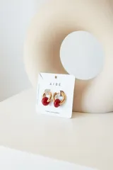 Aros dorados con dije circular de piedra natural negra.