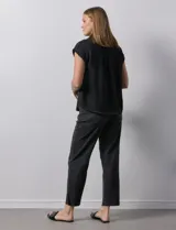 Blusa negra con cuello con solapa y escote en V, con bolsillos delanteros y pespuntes blancos.