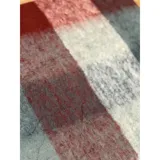 Bufanda rectangular de tejido grueso con diseño de cuadros en tonos azul, naranja, gris y beige, terminada con flecos en los extremos.