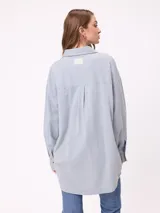 Camisa de manga larga con efecto lavado, corte oversize y cierre frontal con botones. Presenta cuello clásico y logo bordado en el pecho.